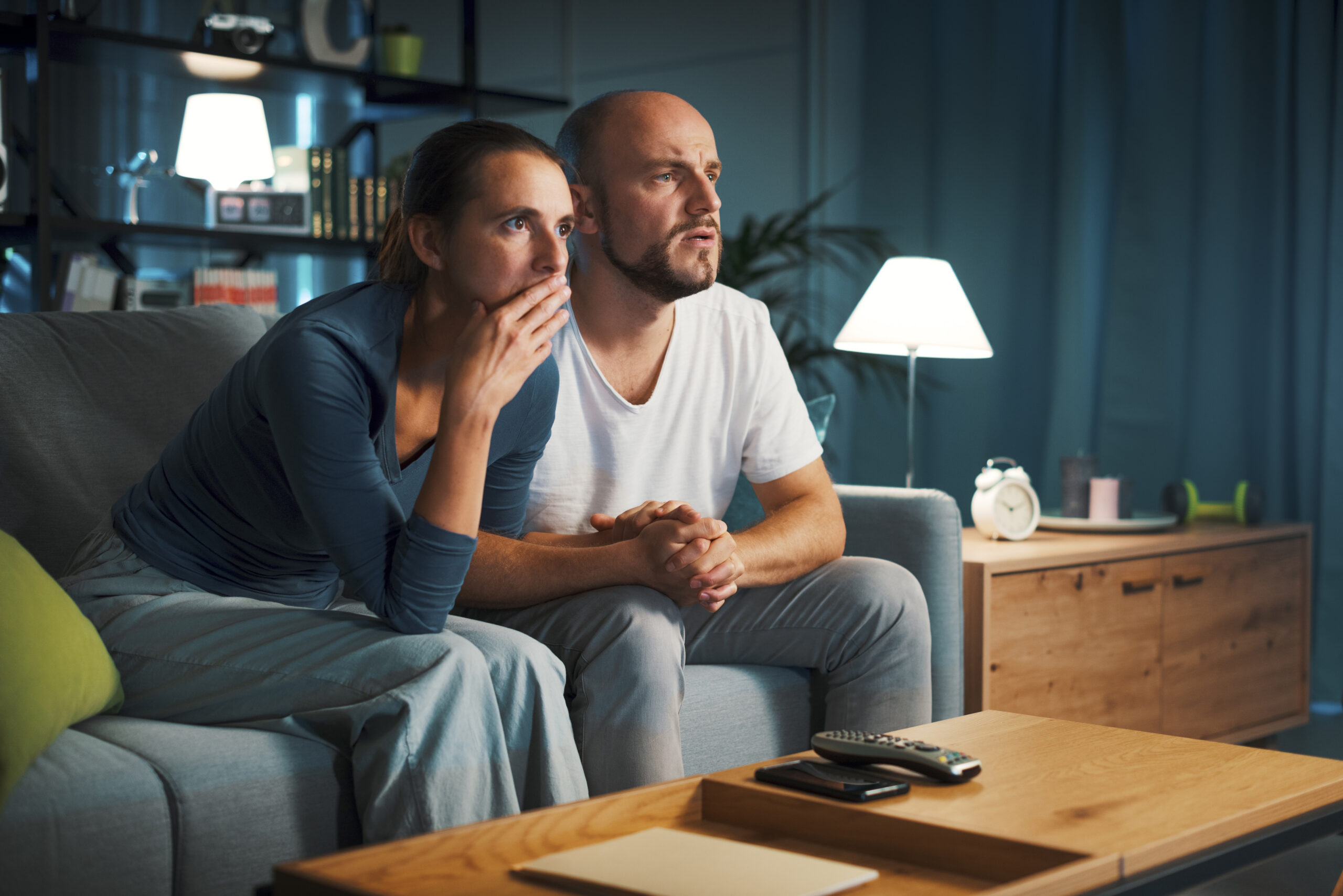 A man and women deeply invested in long-form video content in a modern living room.