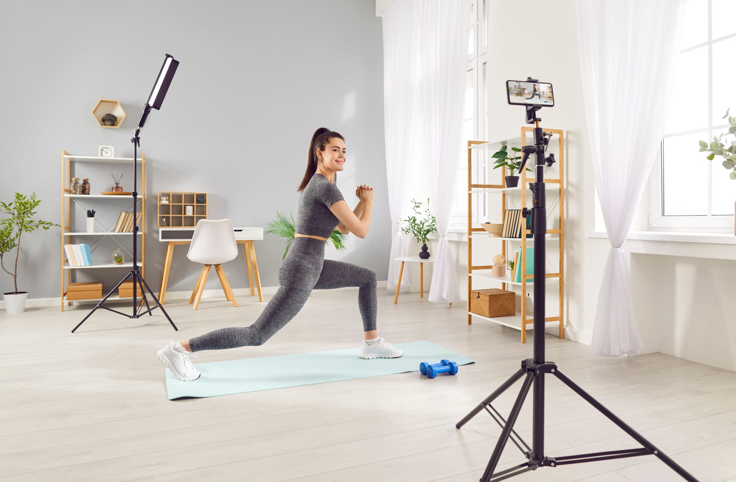 Young woman in workout clothes creating short-form video content on her phone.