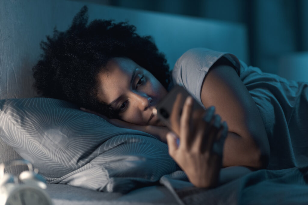 A women in bed watching short-form videos on her iPhone mobile device.