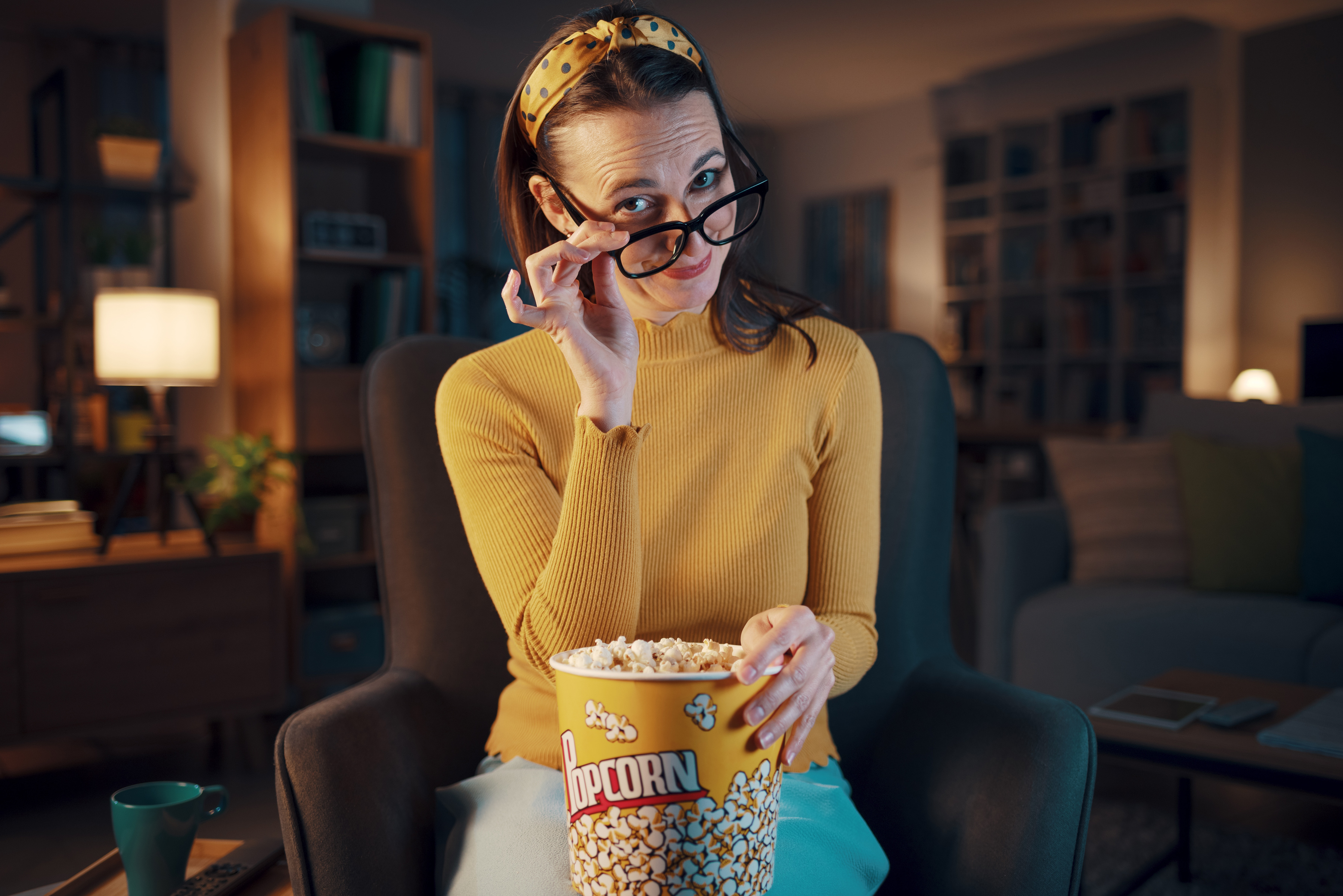 A woman eating popcorn ready for some entertaining long-form content on television.